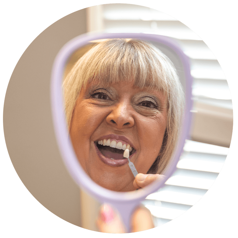 patient holding up veneer to their teeth